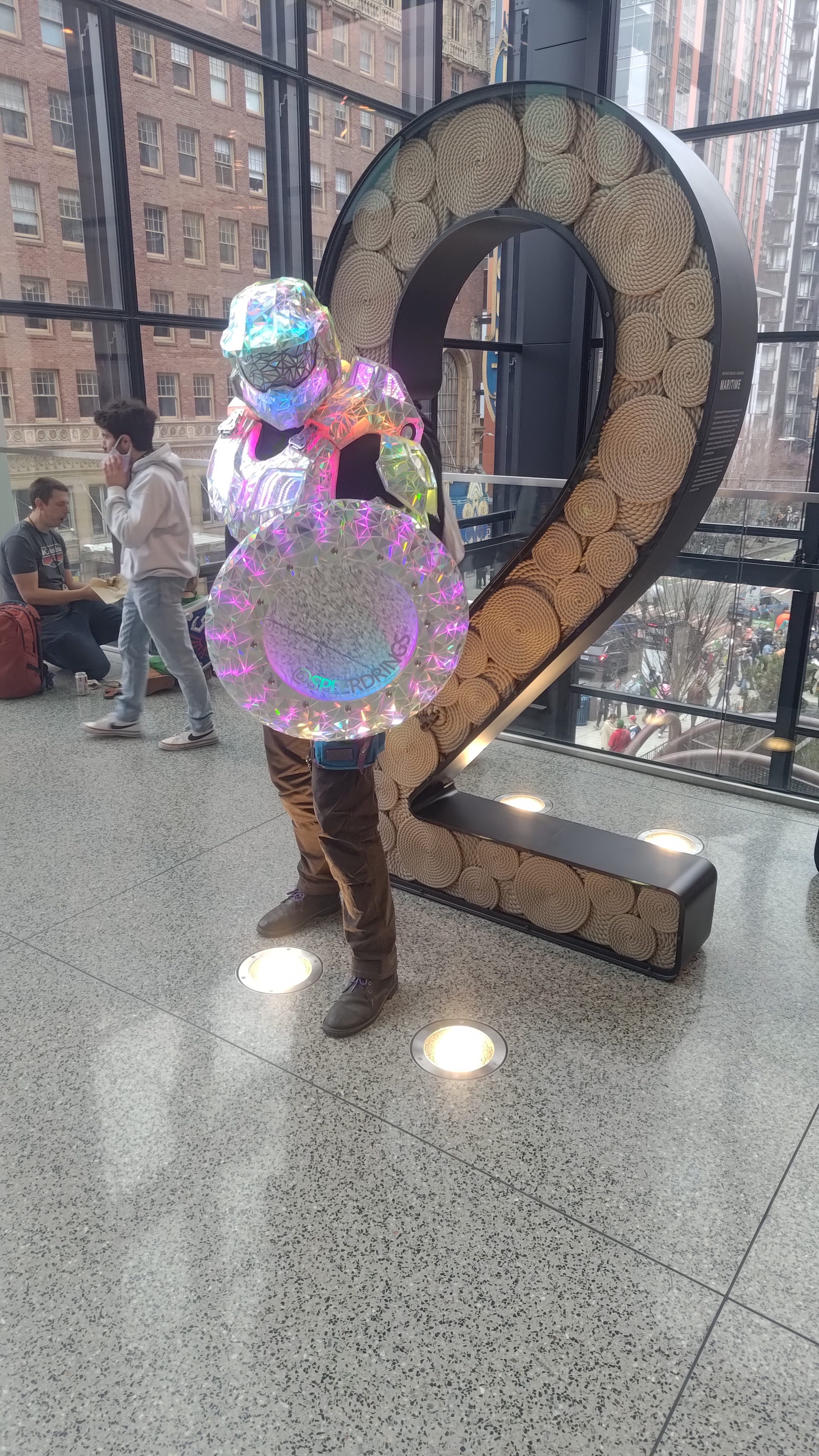 The Disco Chief armour and illuminated shield beside a large sculpture in a convention hall.