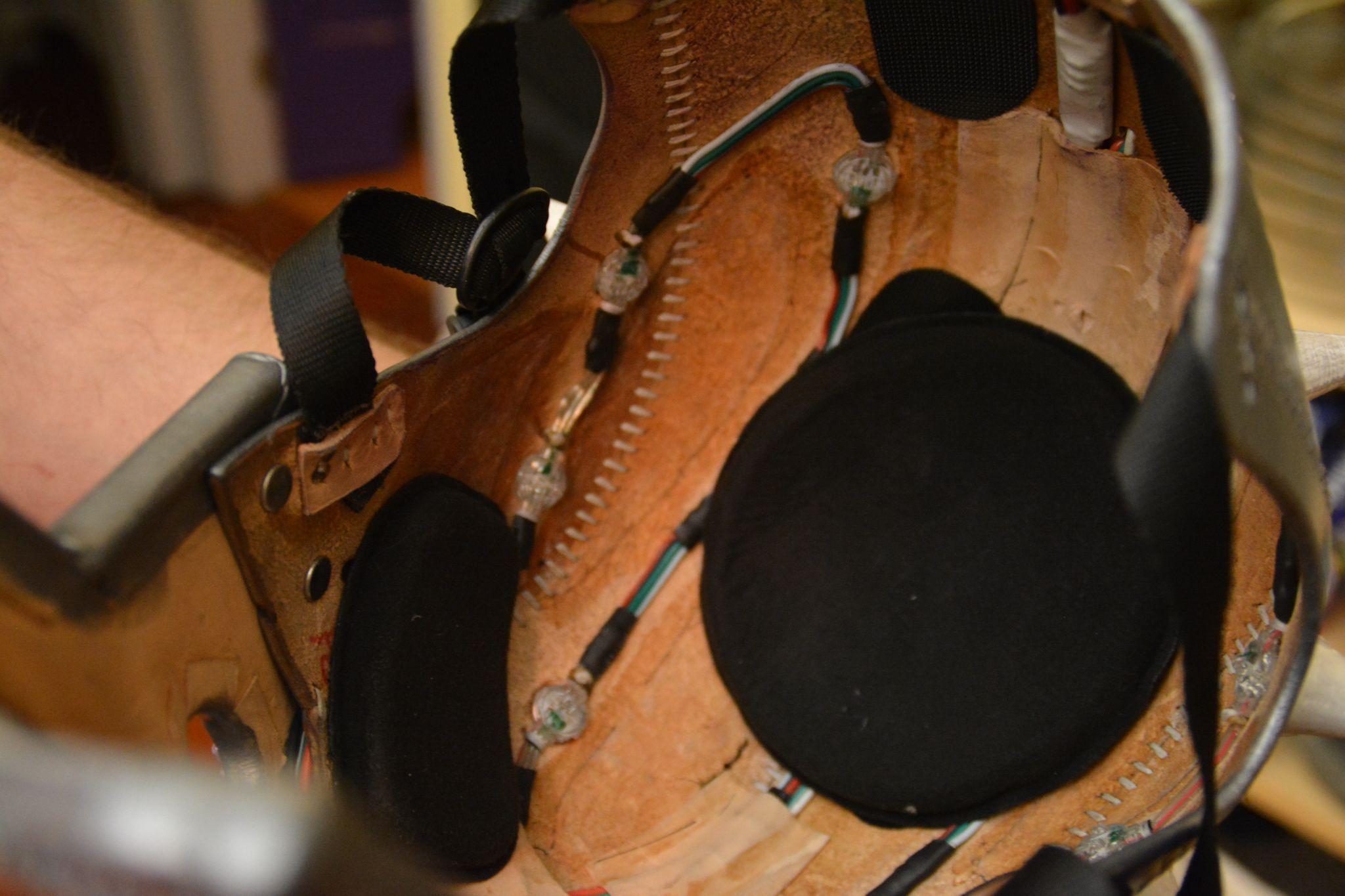The inside of the helmet, showing wired LED nodes, padded rests, and nylon strapping across the leather shell.