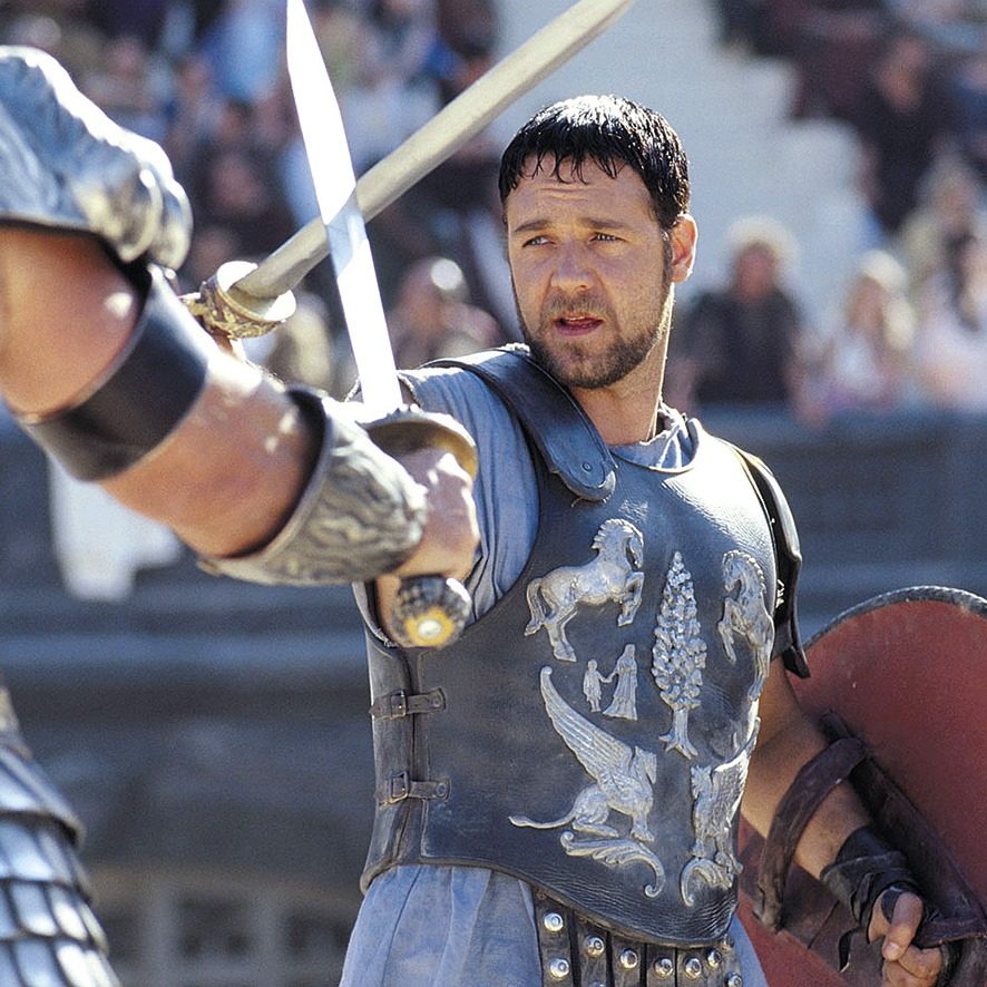 Film still of Maximus raising a sword, his breastplate embossed with two rearing horses.
