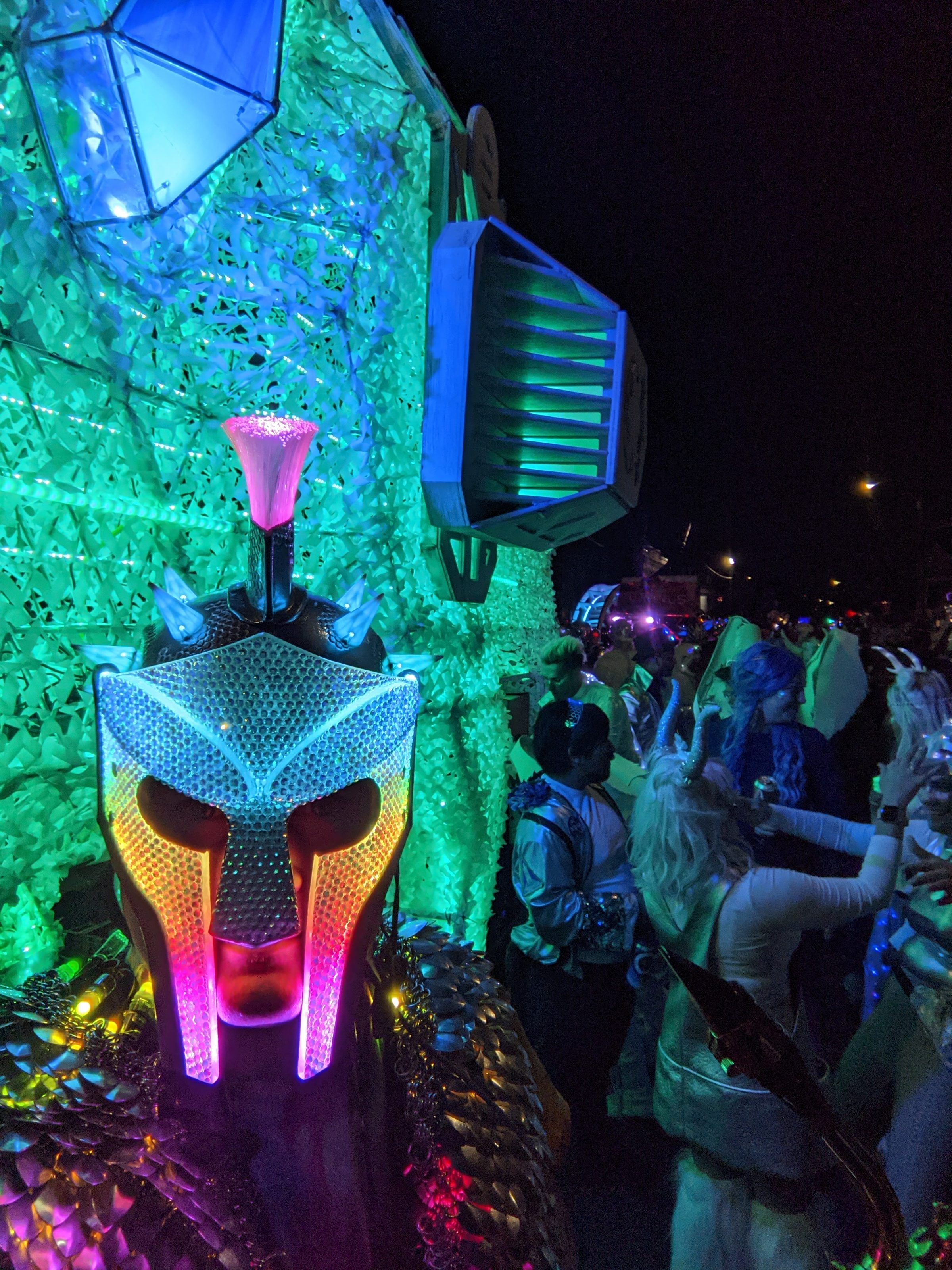 The Russell Glow helmet lit green and magenta in a night-time crowd.