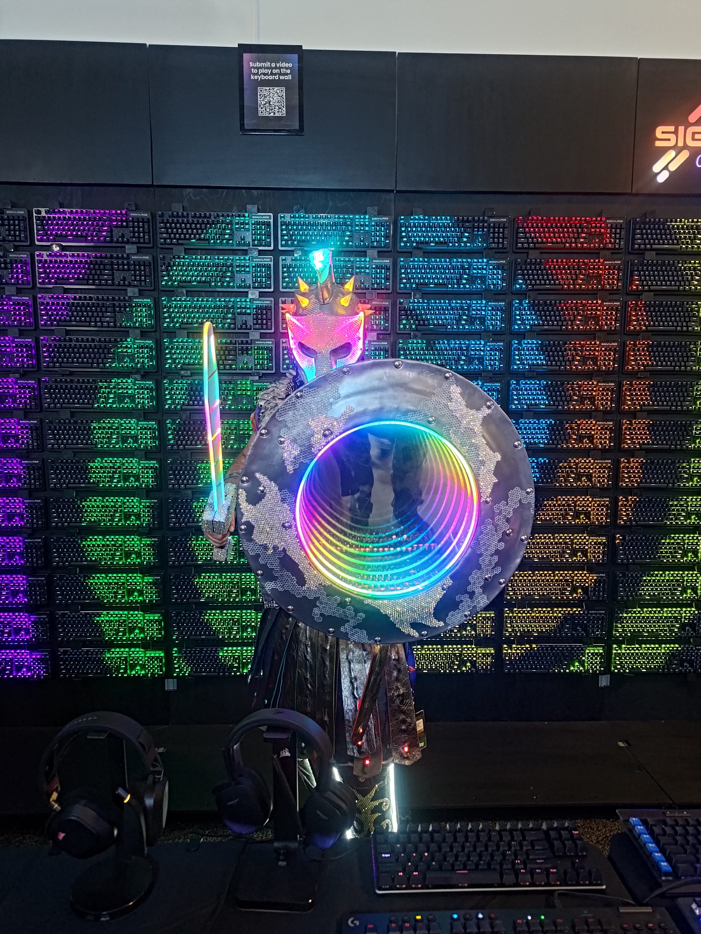 The Russell Glow helmet and shield lit up in front of a wall of illuminated keyboards.