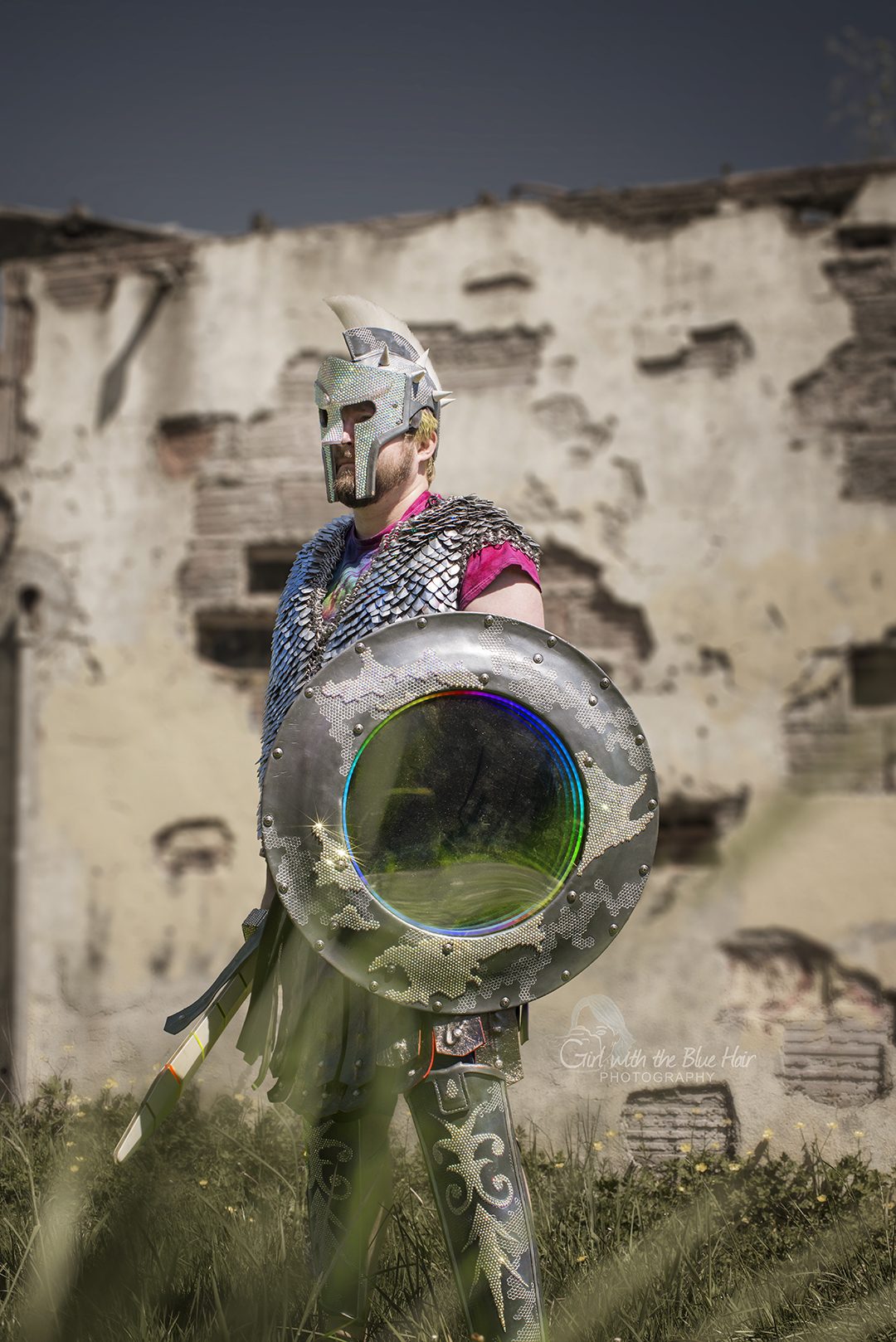 Standing against a ruined brick and plaster wall, the shield held side-on with its mirror catching the light.