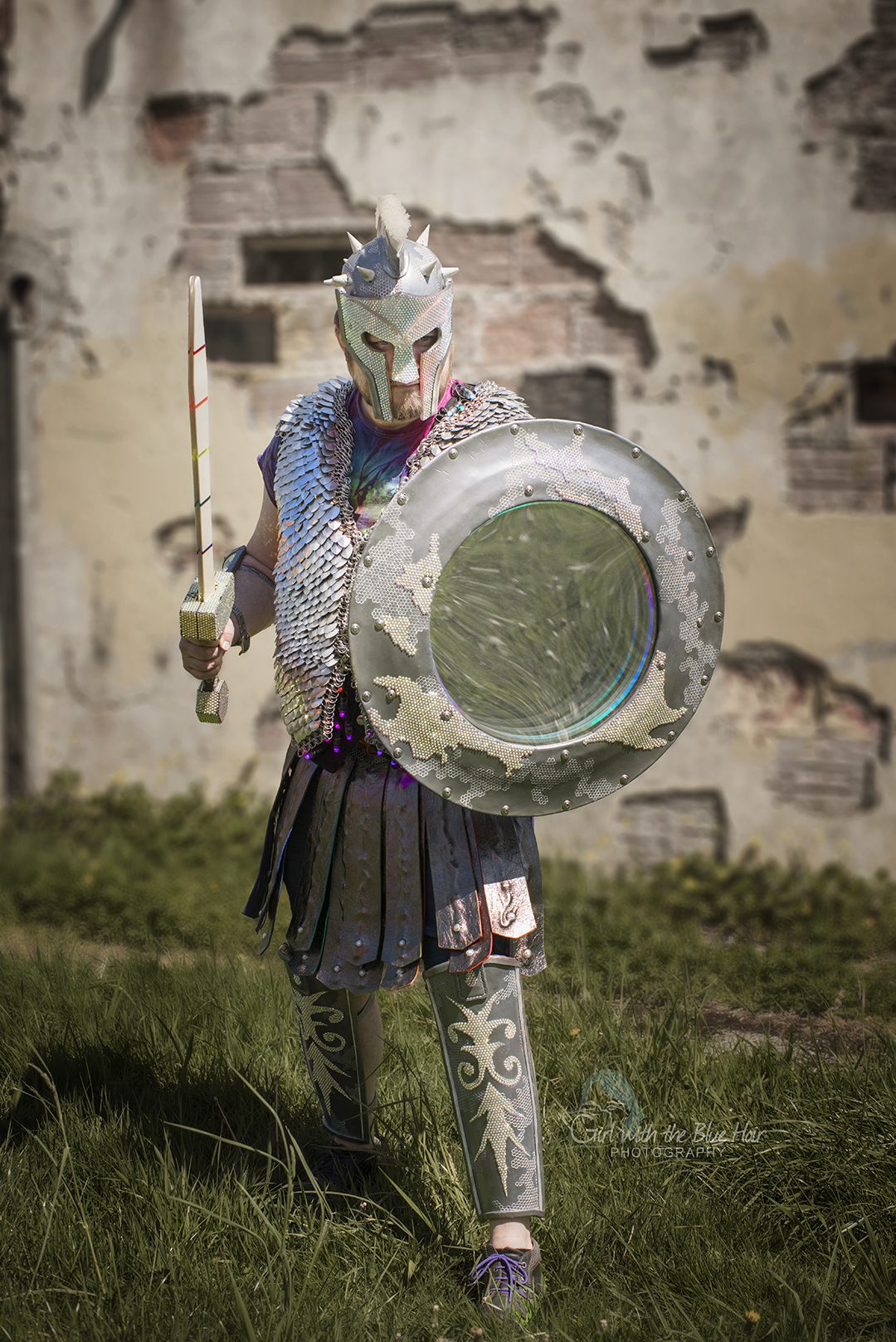 Walking from a ruined wall with the sword raised and the shield held forward.