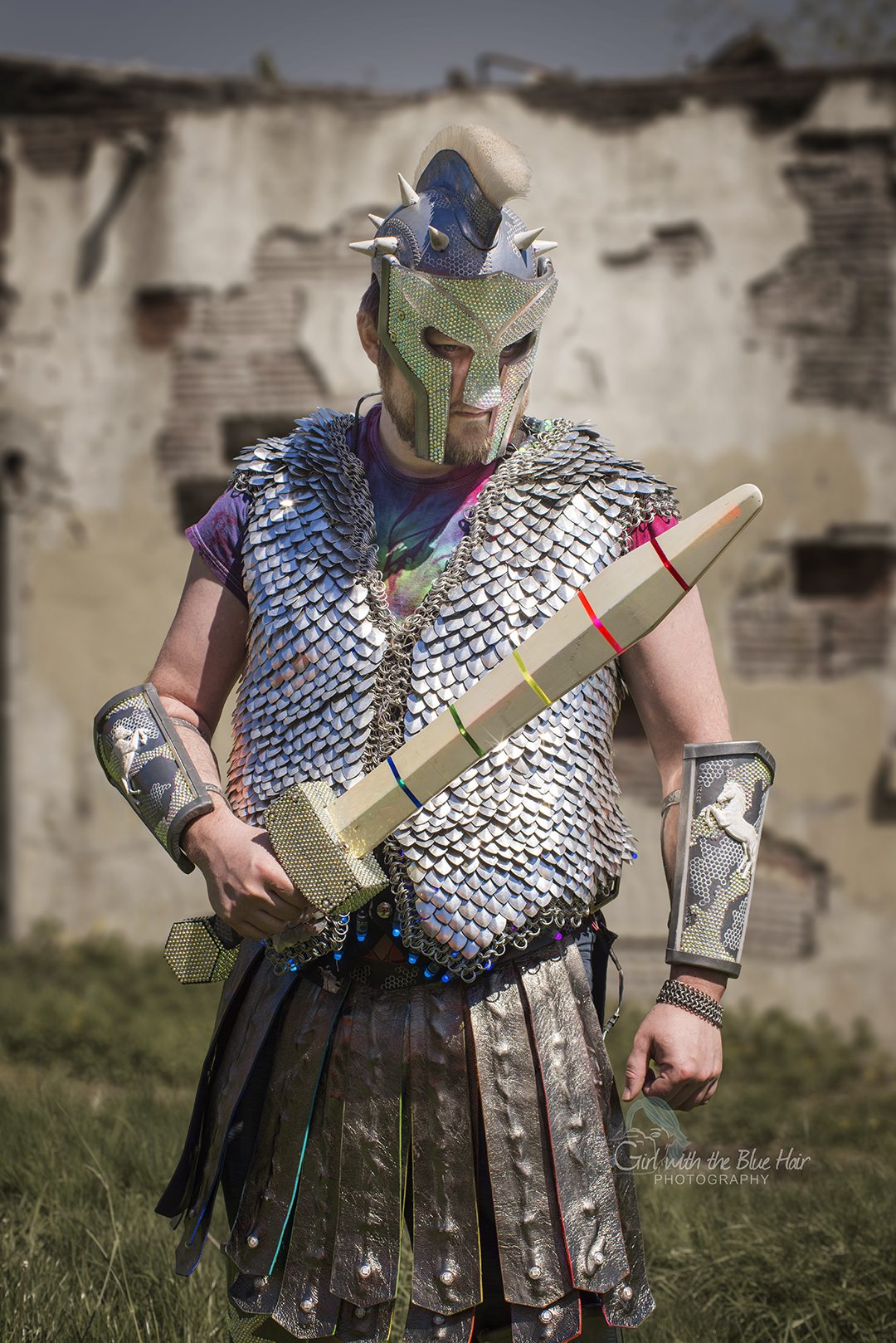 Close three-quarter view against a ruined wall, the sword held across the chest and a rearing horse visible on the bracer.