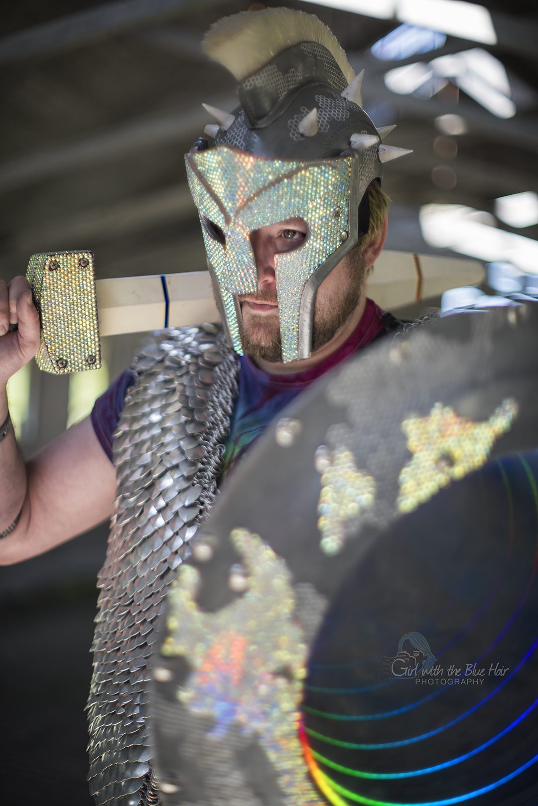 Close portrait under a barn roof, the rhinestoned helmet and the edge of the shield filling the frame.