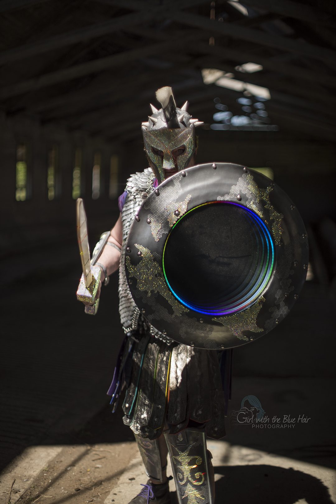Squared to the camera in a dim barn, the shield's lit mirror ring the brightest thing in the frame.