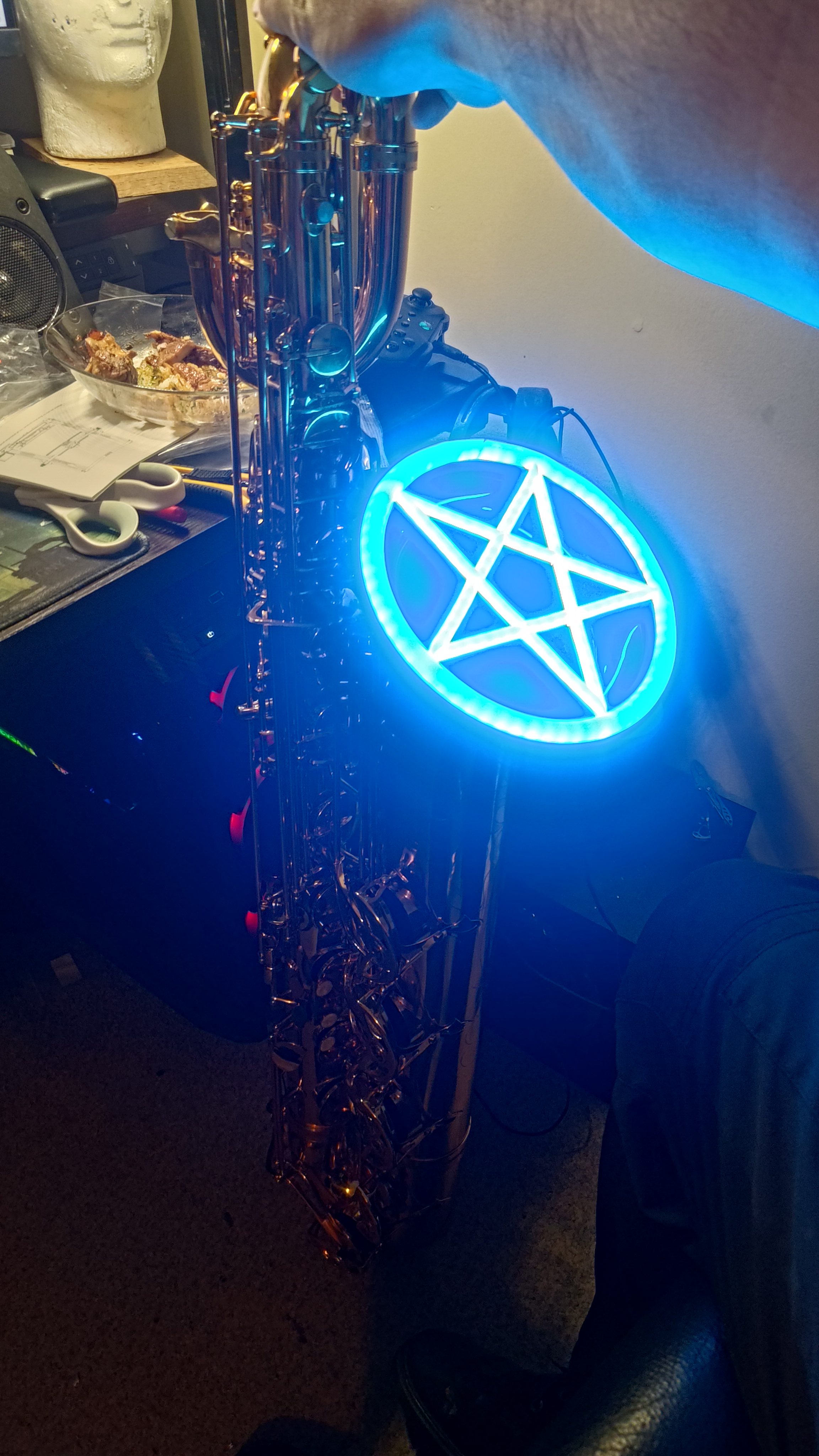 A saxophone fitted with a glowing blue pentagram ring.