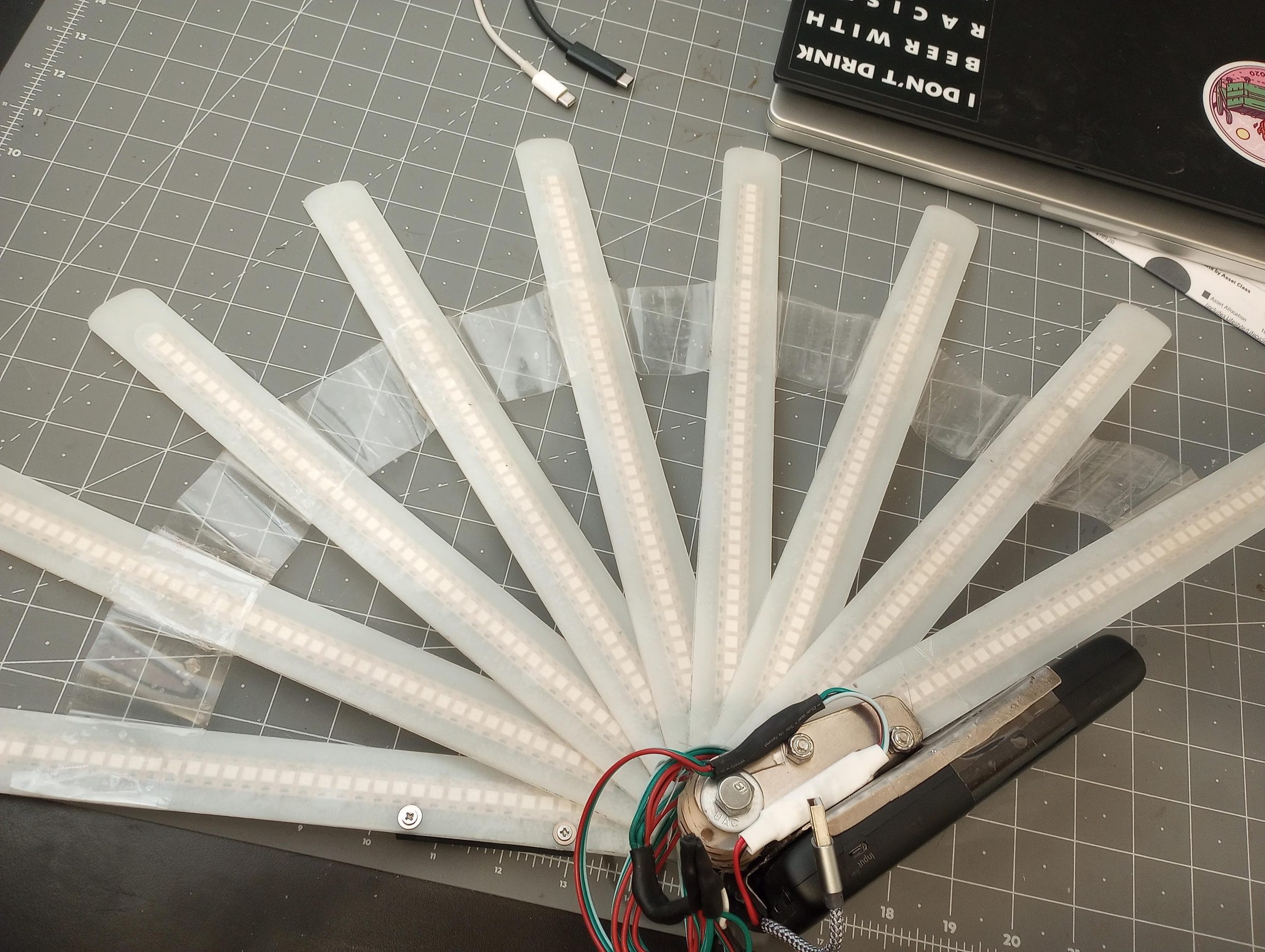 LED tubes and wiring laid out on a cutting mat during the hand fan build.
