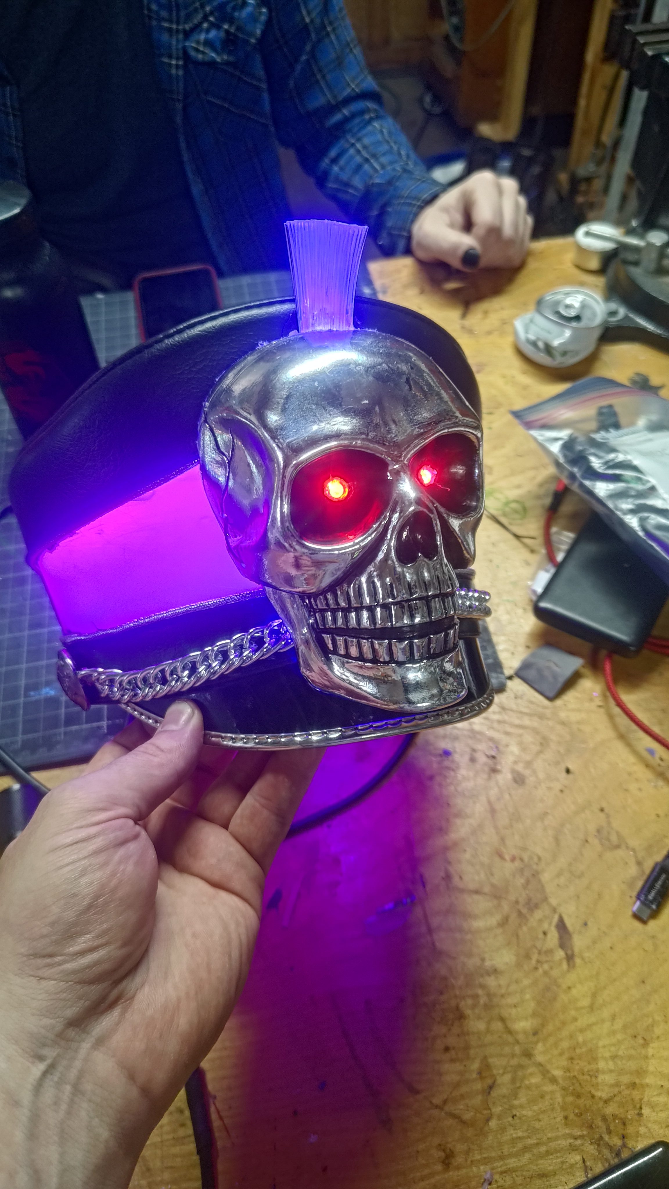 A chrome skull with glowing red eyes mounted on a hat brim.