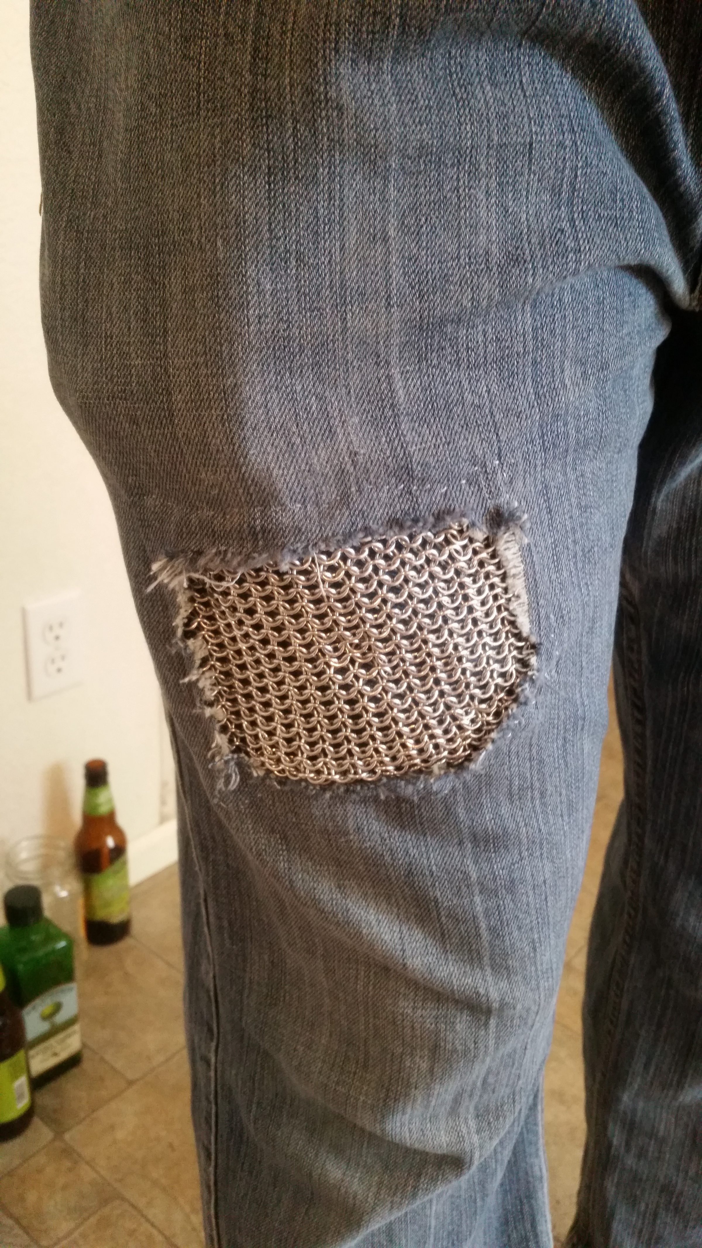 A chainmaille patch set into the knee of a pair of jeans.