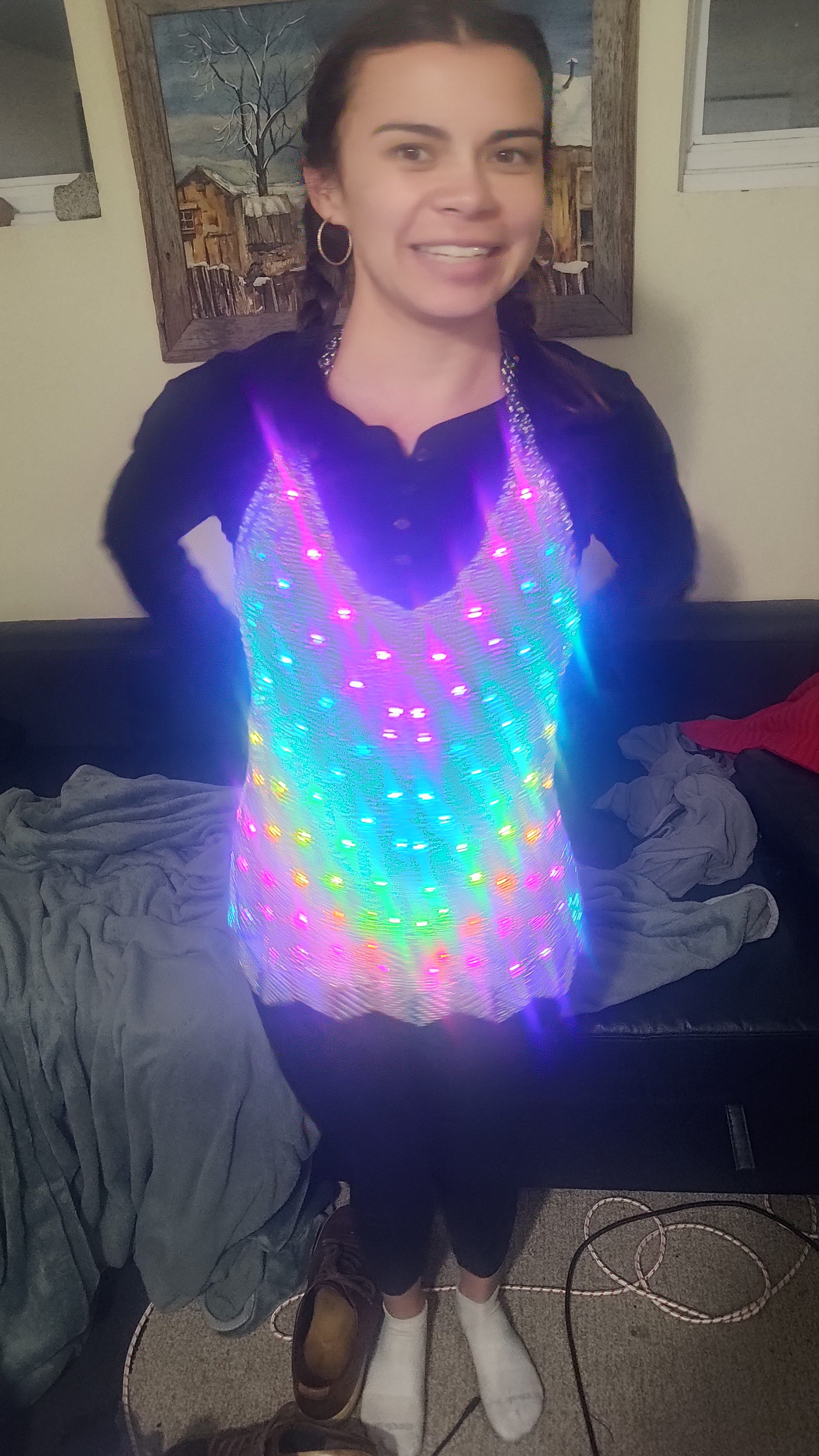 An LED-lit scale vest worn indoors, its scales glowing rainbow.