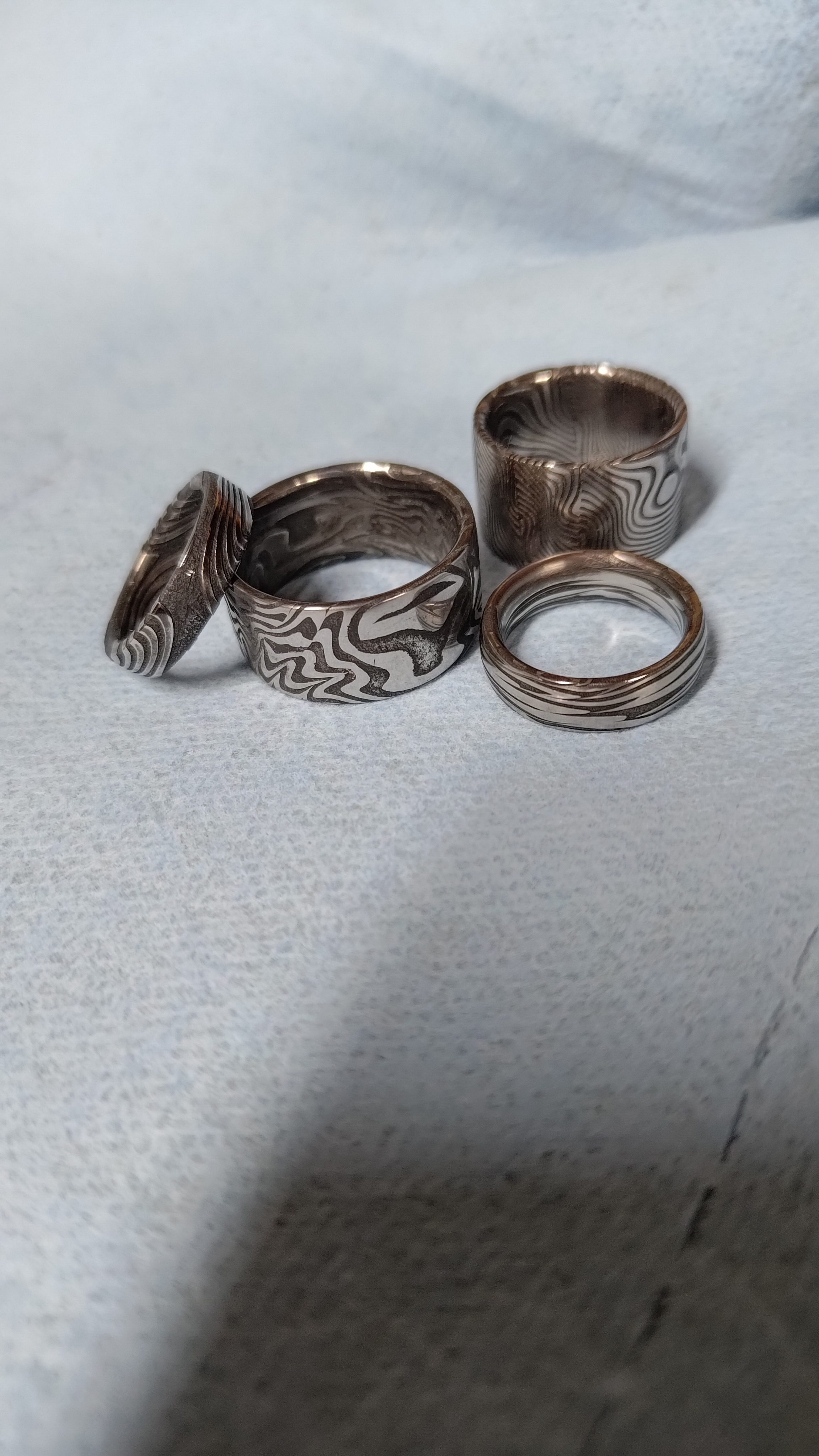 Four damascus rings resting on white cloth.
