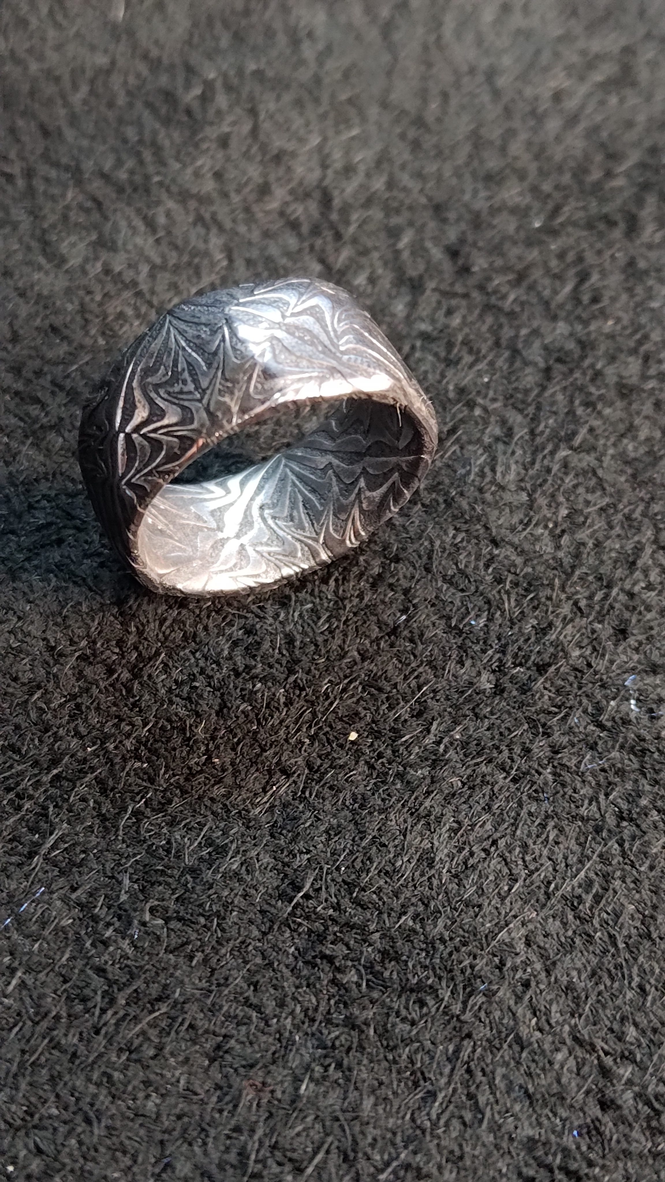 A damascus ring tilted to show the pattern across its face.