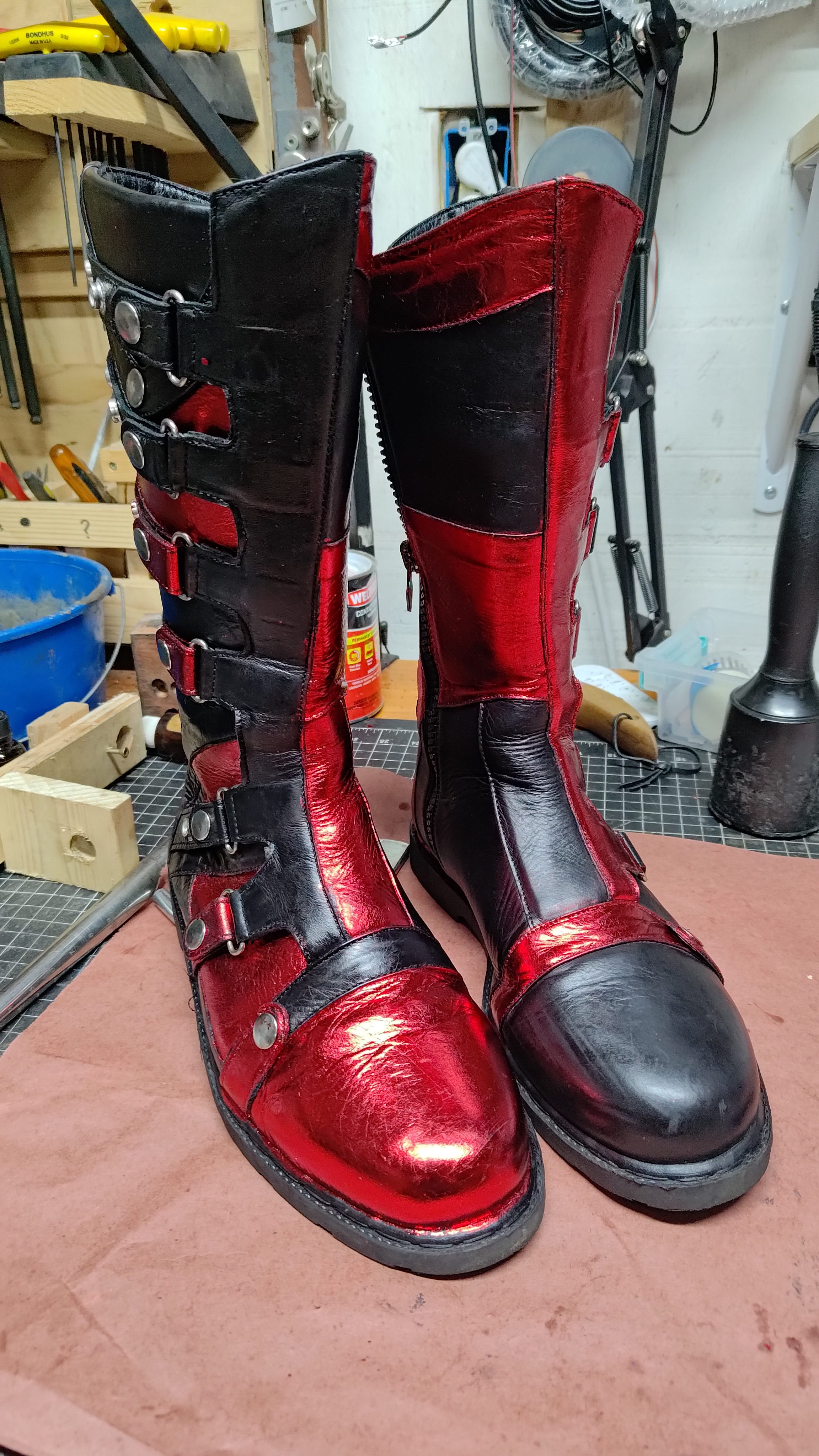 Hand-made black and red leather boots on a workbench.