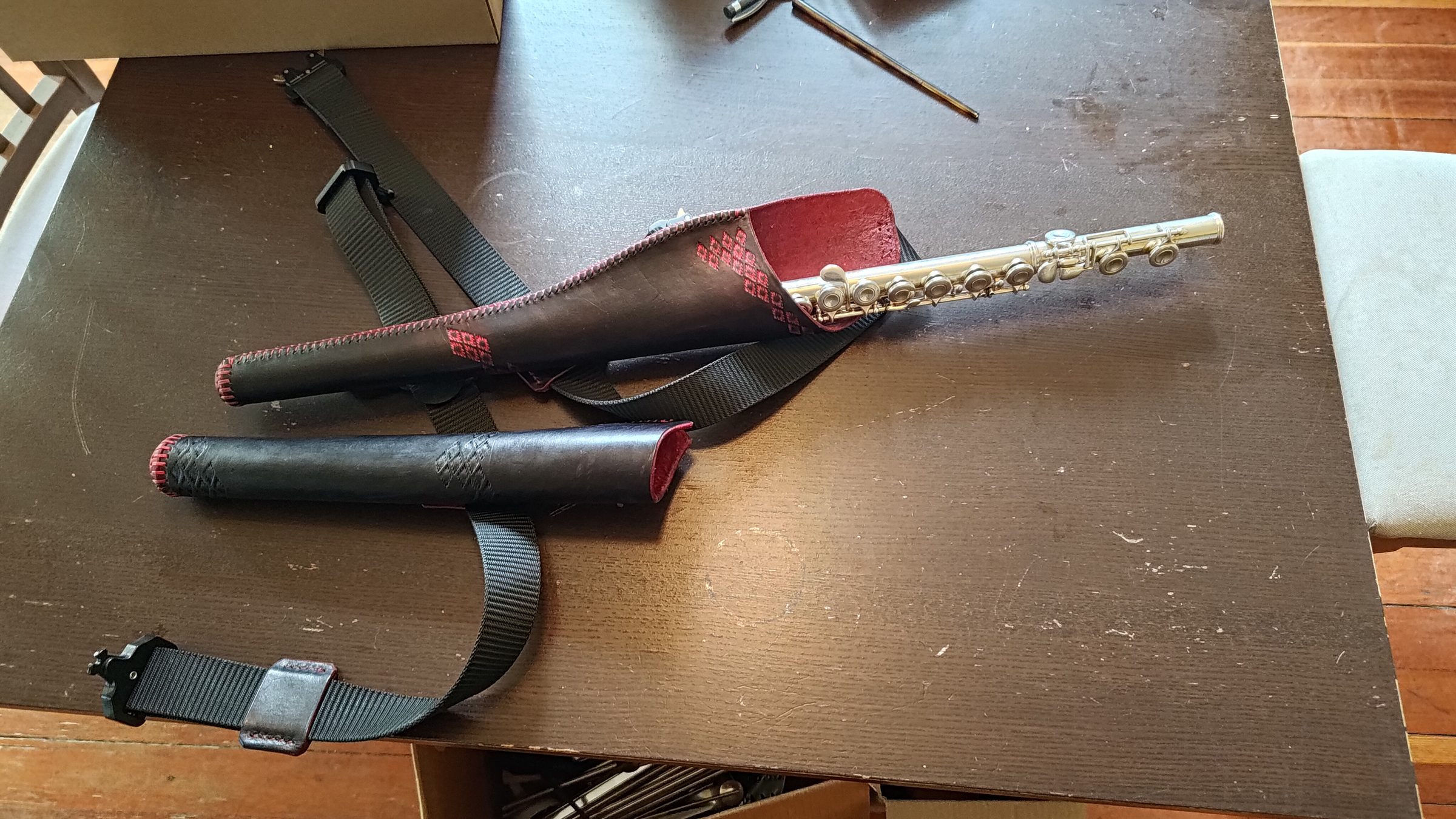 A hand-made leather holster for carrying a flute, with the flute alongside.
