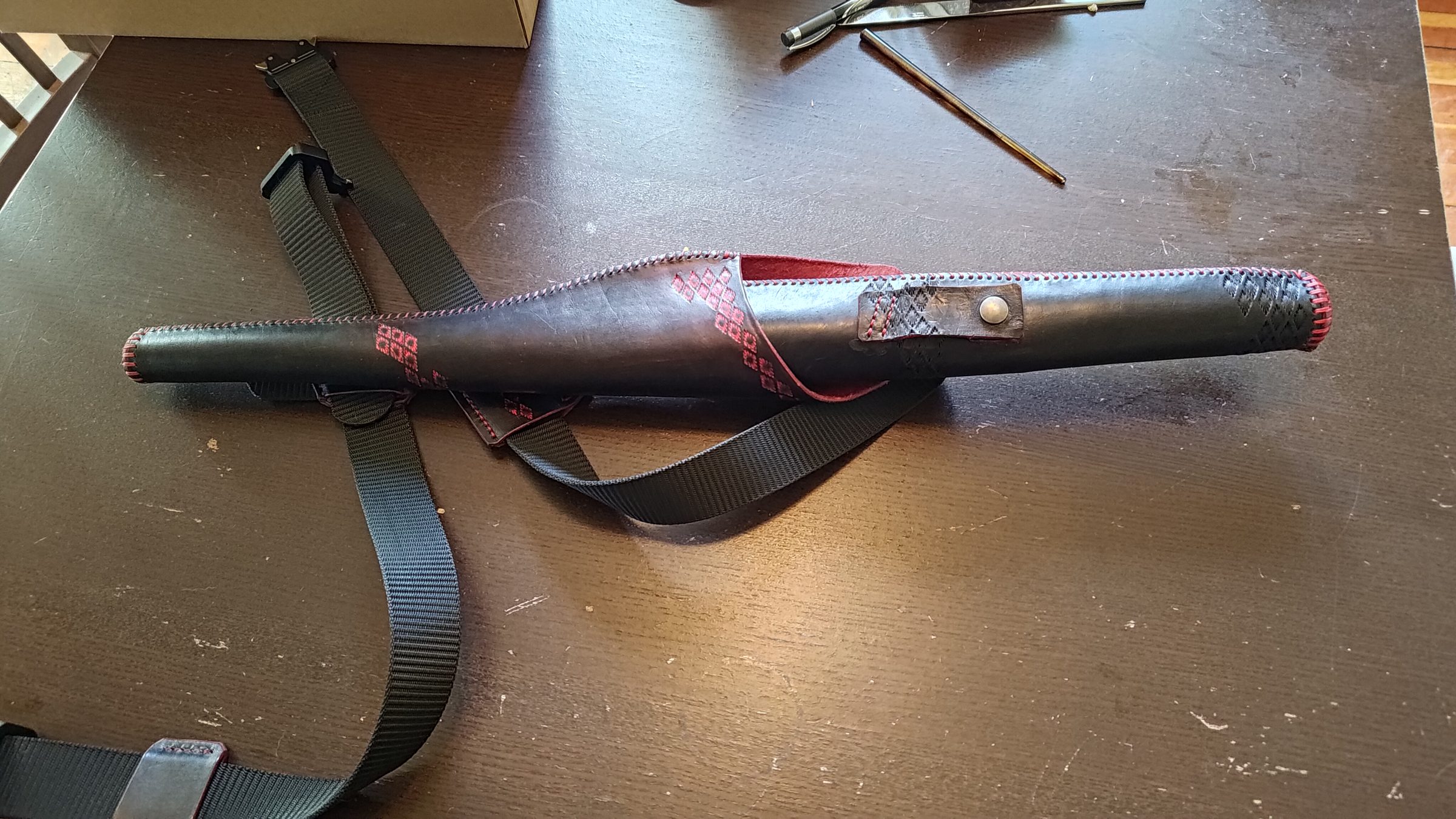 The leather flute holster closed, with its shoulder strap laid out.