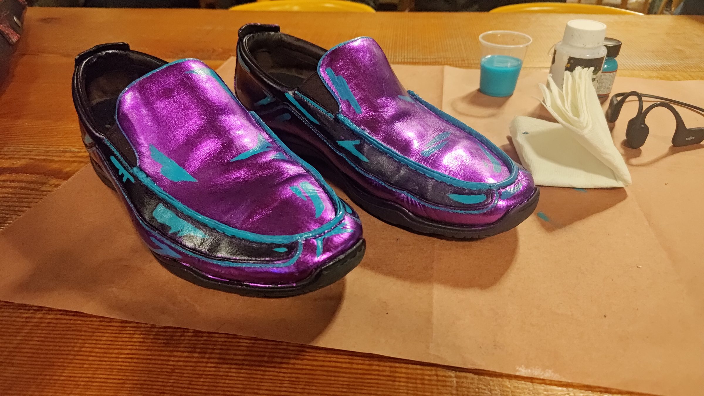 Hand-made purple and blue leather shoes on a workbench.