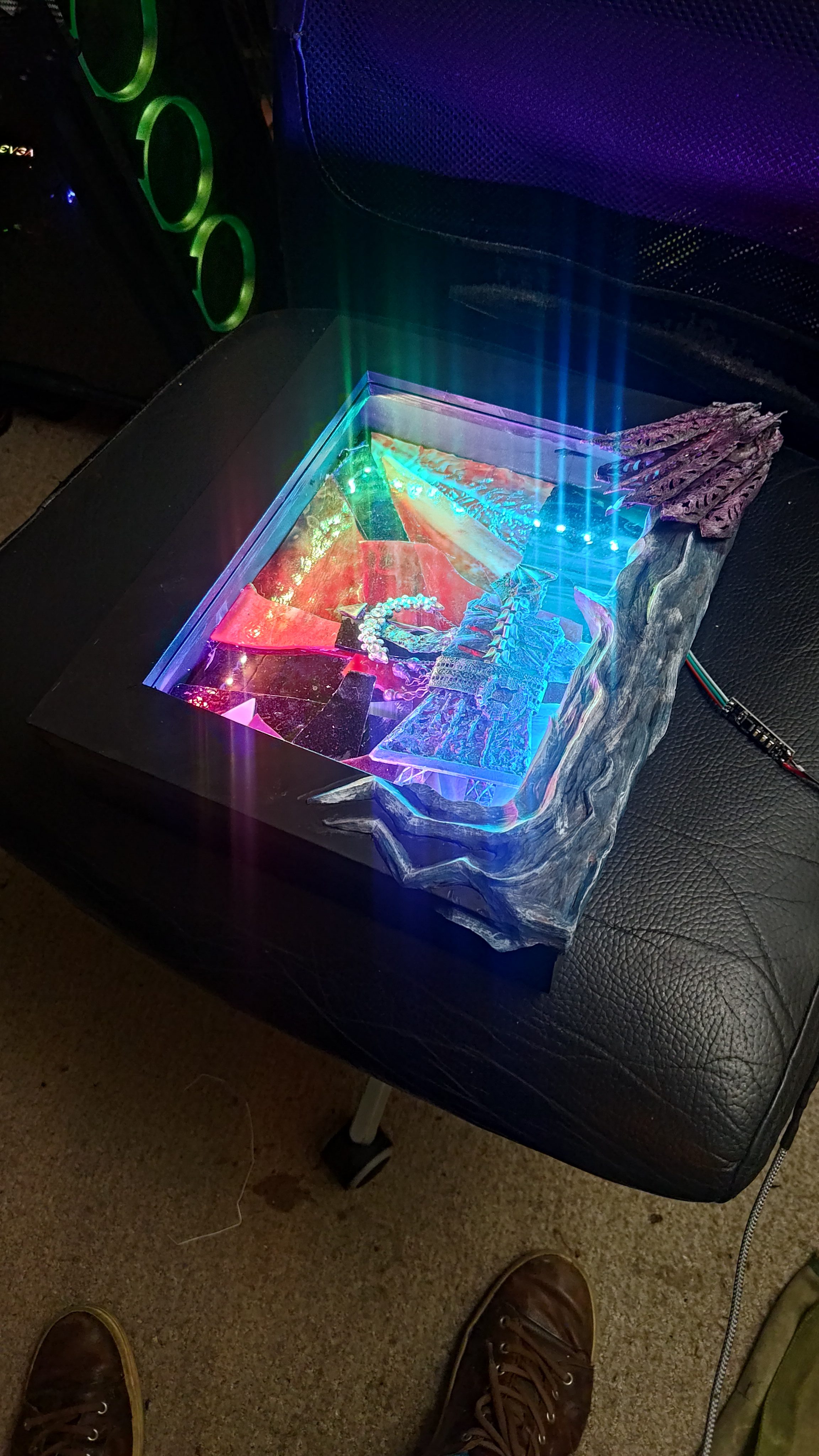 The metal, glass, and LED panel lit up, colour glowing through the textured glass.
