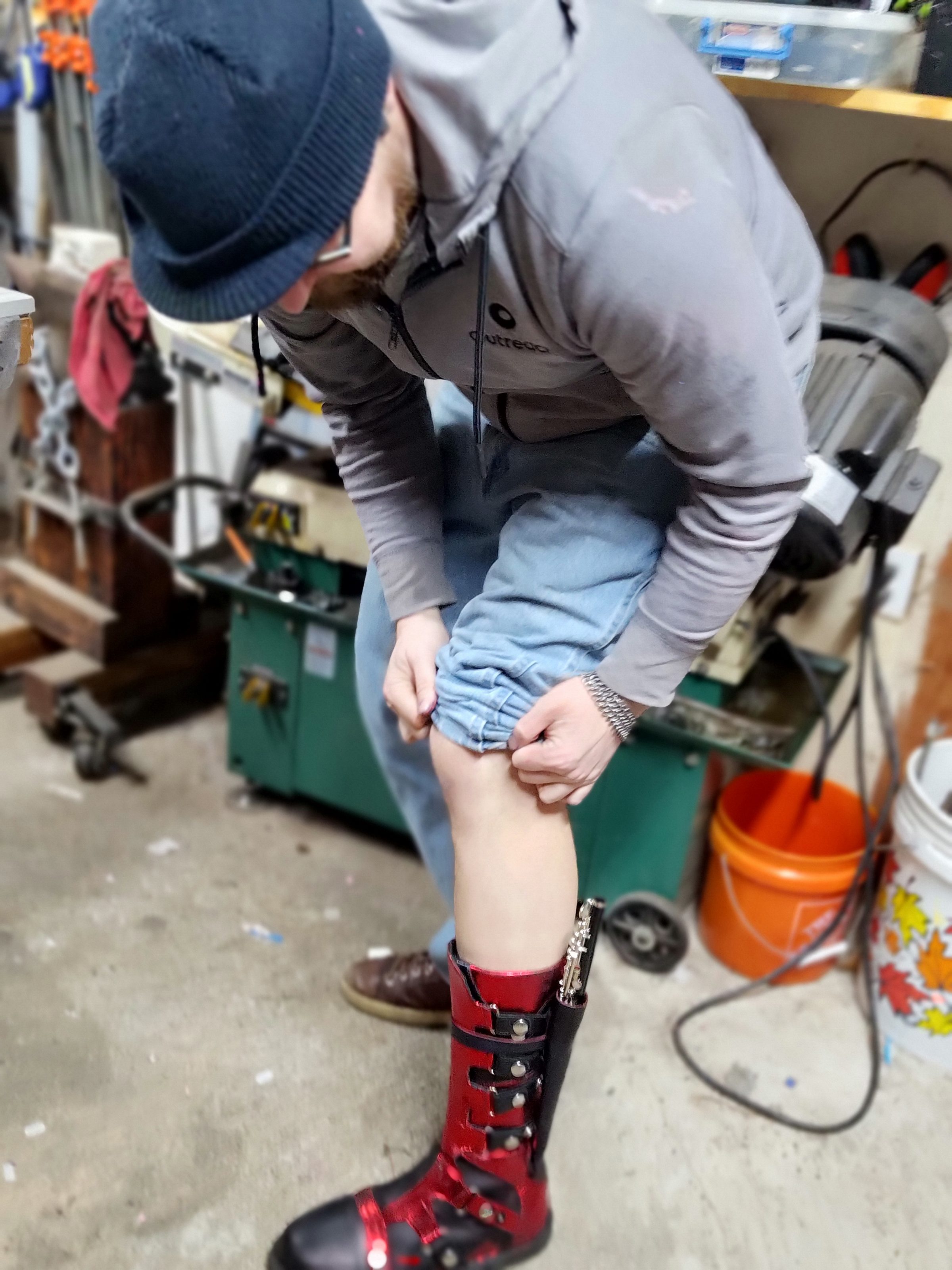 The hand-made black and red leather boots worn in the workshop, seen from the side.